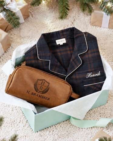Julegavetip til ham med marineblå flannelpyjamas og cognacfarvet toilettaske broderet med valgfrit navn