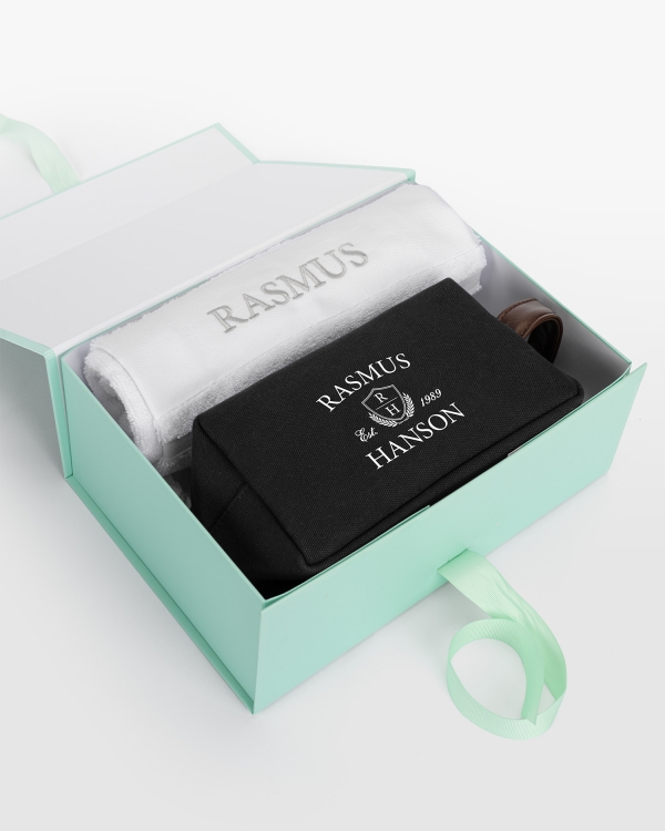 Hvidt håndklædesæt (50x70) med sølvbroderi og sort lærredsnecessær med navnetryk, til elegant personlig stil.