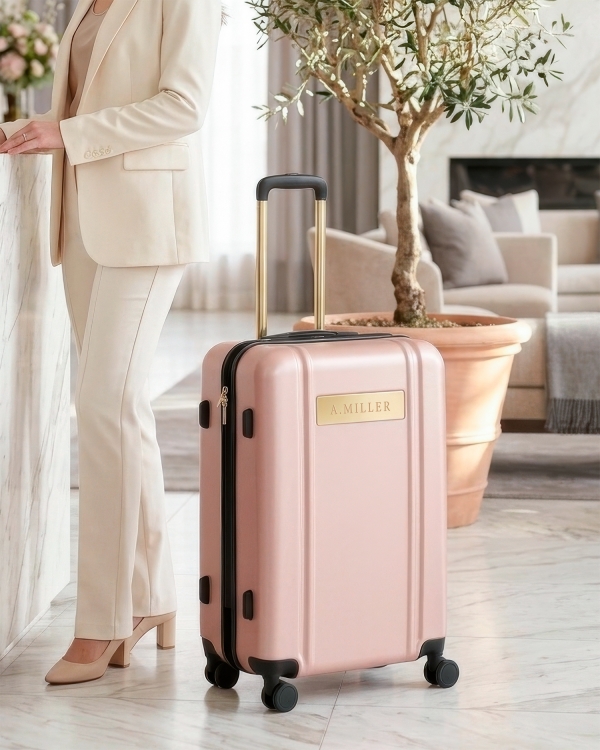 Lyserød kuffert med guldfarvede detaljer og navn