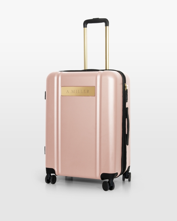 Lyserød kuffert med navn og gulddetaljer