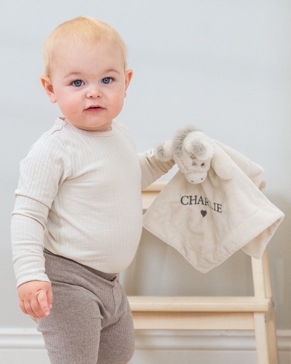 Nusseklud i cremefarve, broderet med barnets navn.