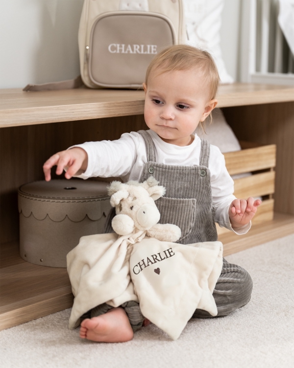 Nusseklud formet som en giraf med broderet navn i brun