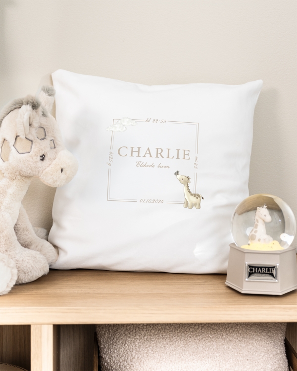 Hvidt pudebetræk med trykt girafmotiv samt navn og dato
